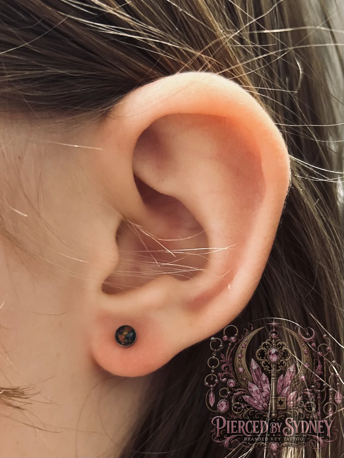 Ear piercing with black jewelry by Sydney